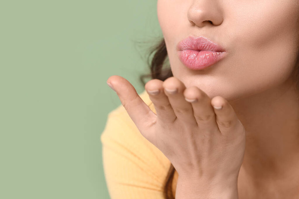 Young woman blowing kiss on green background, closeup - Photo, Image