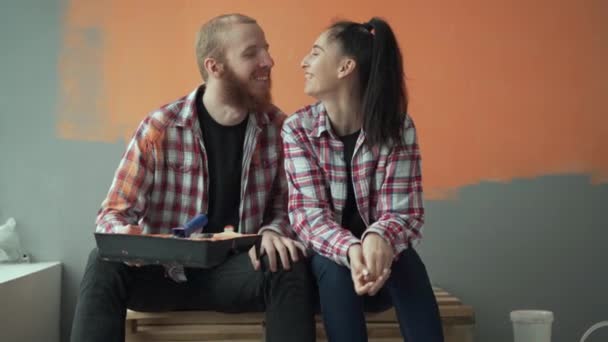 Háztartási javítási és dekorációs koncepció. Fiatal szerető pár tervezi otthoni javítás a nappaliban, és ölelkezve a szerelemmel. Fénymásolási hely - Felvétel, videó