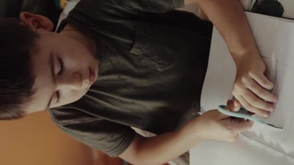 Kind schneidet weißes Papier mit Schere am Wohnzimmertisch. Kinder-Kreativ- und Bastelworkshop - Filmmaterial, Video