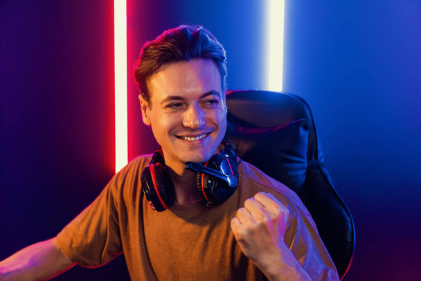 Host channel of gaming smart streamer playing online game to be winner, wearing headphone with viewers live steaming on media social online for selected team competition at neon light room. Pecuniary. - Photo, Image