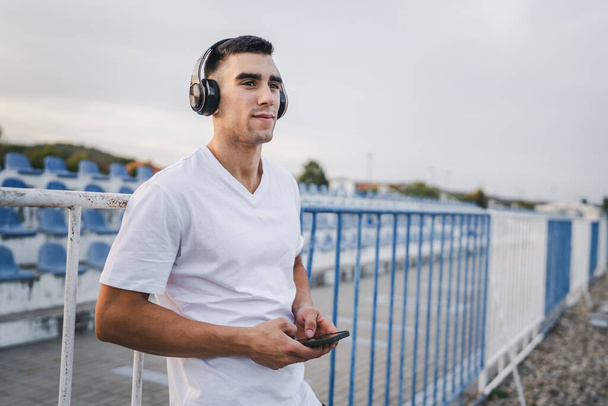 Ritratto di un atleta che usa il cellulare durante la corsa mattutina L'uomo atletico che ascolta musica sulle cuffie utilizza l'applicazione dell'app per telefoni cellulari - Foto, immagini