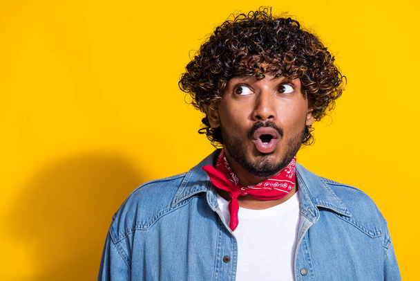Photo portrait of attractive young man look shocked empty space dressed stylish denim clothes red scarf isolated on yellow color background. - 写真・画像