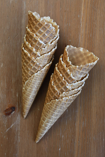 Deux cônes de gaufres brun doré croustillants se tiennent debout sur une table en bois, prêts à être remplis de délicieuses glaces  - Photo, image