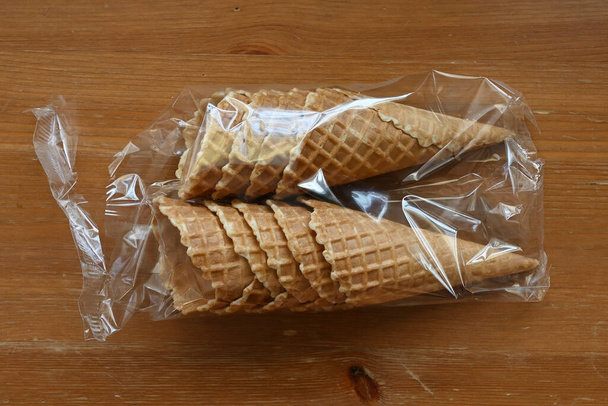 cones waffle em embalagens plásticas em uma mesa de madeira, pronto para ser preenchido com delicioso sorvete  - Foto, Imagem