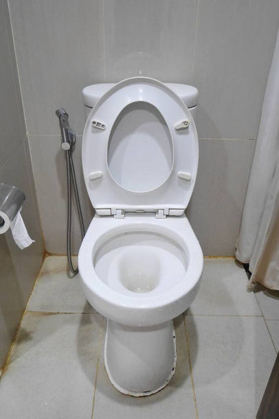 Toilettensitz befindet sich in der offenen Position. Das Badezimmer ist schmal und mit Taschentuch an der Wand ausgestattet - Foto, Bild