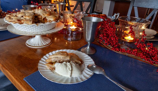 Snijd van zelfgemaakte gourmet appeltaart op een vakantietafel met kaarsen en verlichting. - Foto, afbeelding