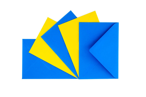 白い背景に配置された青と黄色の紙の封筒のコレクション - 写真・画像