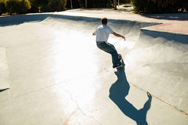 Full body of young male skater in casual outfit doing trick on skateboard riding in skate park - Φωτογραφία, εικόνα