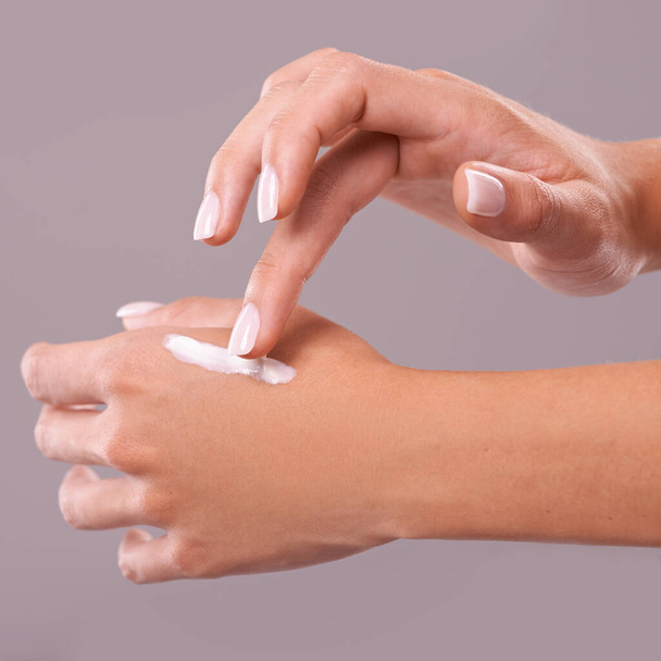 Hands, cream and beauty with woman for skincare, dermatology and wellness on grey background. Moisturizer, lotion or sunscreen with nails and manicure, antiaging cosmetic product and skin health. - Photo, Image