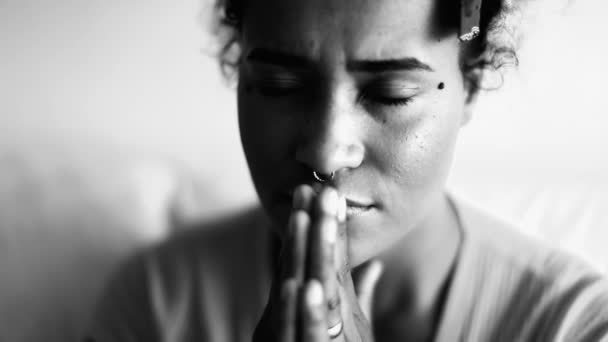 jovem mulher afro-americana fiel em oração contemplativa em casa com as palmas das mãos juntas em meditação tranquila olhando para cima com esperança e GRATITUDE, monocromático - Filmagem, Vídeo