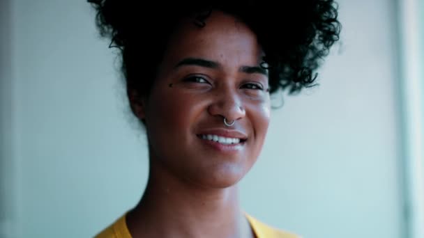 Een jonge Zuid-Amerikaanse zwarte vrouw van Afrikaanse afkomst glimlachend naar cameraportret. 20s vrouwelijke persoon met vriendelijke houding - Video