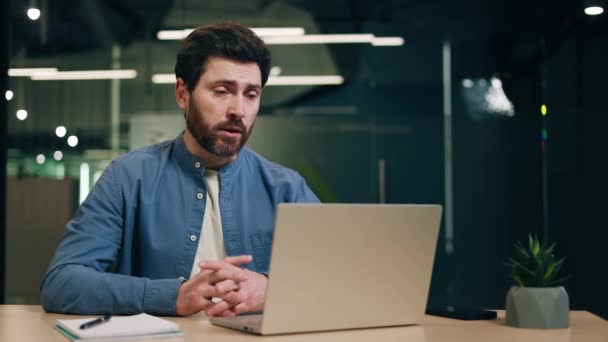Homme concentré en chemise bleue assis devant un ordinateur portable et parlant lors d'une réunion vidéo en ligne. Gestionnaire des ressources humaines homme interviewant le candidat pour le poste et expliquant les détails du travail. - Séquence, vidéo