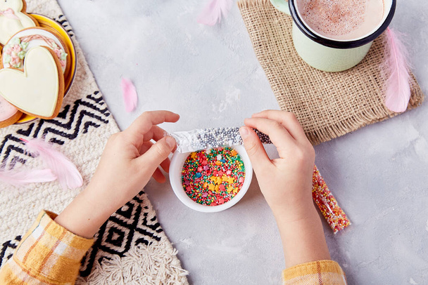 Osterfreude mit dekorierten Plätzchen mit Streusel von Kinderhänden zwischen süßem Kakao und Pastell-Plätzchen. - Foto, Bild
