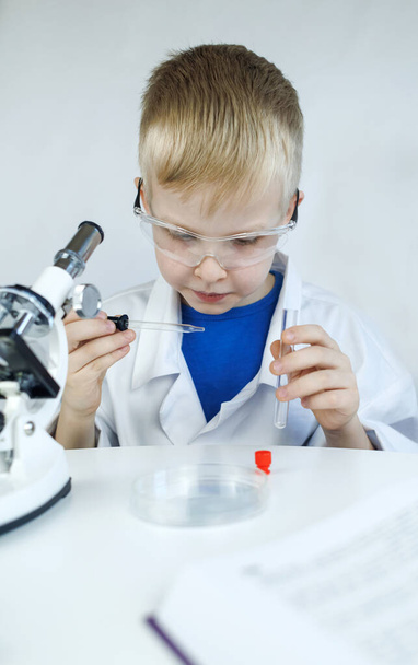 Químico infantil. El profesor muestra un experimento visual. Un mentor científico enseña un enfoque experimental. Microscopio, placa de Petri, pipetas, libros. Trabajo práctico en química o física. Trabajos de laboratorio - Foto, imagen