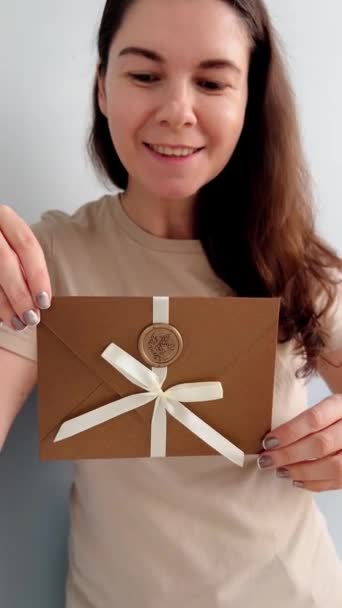 εκπτωτική κάρτα ή πιστοποιητικό δώρου σε φάκελο σε γυναίκα που φοράει μπεζ T-shirt χέρια σε λευκό φόντο - Πλάνα, βίντεο