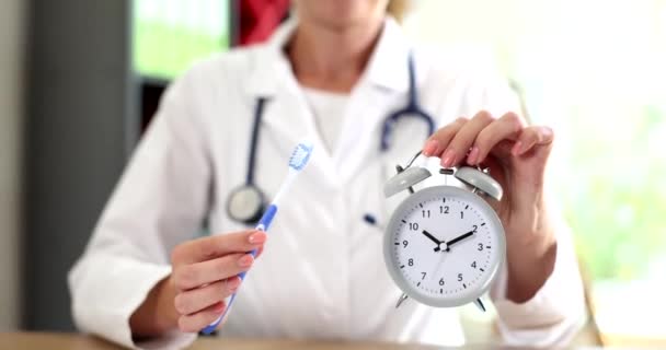 歯医者は口腔衛生の間、歯ブラシと目覚まし時計を手に持っています。歯科病院で働く歯科医 - 映像、動画