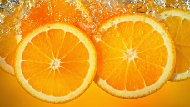 Супер повільний рух свіжих апельсинових часточок падають і течуть у воді на швидкості 1000 фунтів стерлінгів. Знято з високошвидкісною кінокамерою у роздільній здатності 4K. - Кадри, відео
