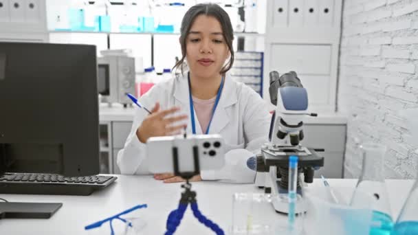 Латиноамериканка записывает видео в лабораторных условиях, анализируя образцы и демонстрируя эксперименты. - Кадры, видео