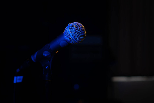 Nahaufnahme eines Mikrofons mit blauer Hintergrundbeleuchtung in einem Musikstudio, bei einem Konzert im dunklen Kopierraum - Foto, Bild