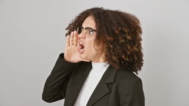 Wütende junge hispanische Frau mit lockigem Haar schreit laut ins Leere, ihre Hand an den Mund geklemmt, vor einem isolierten weißen Hintergrund stehend. Ausdrucksstarke Kommunikation vom Feinsten. - Filmmaterial, Video