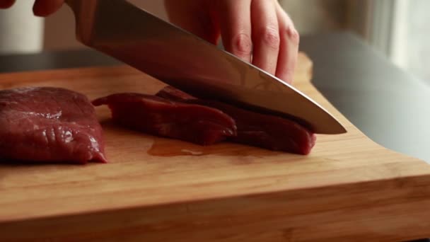close-up foto 's van de handen van de vrouw vakkundig snijden rundvlees in reepjes op een houten plank.  - Video