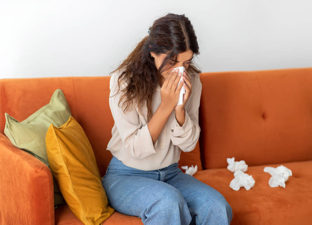 Doente jovem mulher soprando nariz em tecidos de papel enquanto sentado no sofá em casa, retrato de Ill Millennial feminino sofrendo Runny Nariz ou chorando, sentindo-se mal, tendo gripe sazonal, espaço livre - Foto, Imagem
