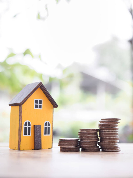 Miniaturhaus und Stapel von Münzen. Das Konzept des Sparens Geld für Haus, Immobilieninvestitionen, Haus Hypothek, Immobilien - Foto, Bild