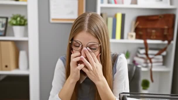 Εξαντλημένη νεαρή ξανθιά επιχειρηματίας που τρίβει κουρασμένα μάτια στο γραφείο, εκφράζοντας πονοκέφαλο, άγχος και προβλήματα όρασης - Πλάνα, βίντεο