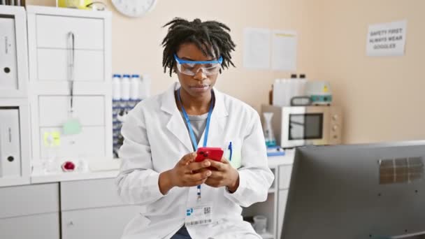 Confident and serious, young black woman with dreadlocks works in lab, pointing at you with one finger, the gesture on camera. on her phone yet leading and proud - Footage, Video