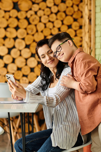 fröhlicher Junge mit Down-Syndrom, der Zeit mit seiner schönen Mutter im Café mit Telefon und Speisekarte verbringt - Foto, Bild