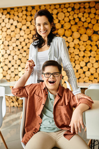 привлекательная веселая мать смотрит в камеру, проводя время со своим сыном с синдромом Дауна - Фото, изображение