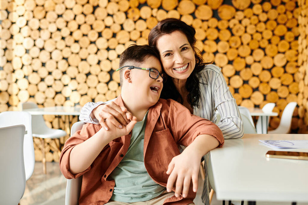 atractiva madre alegre mirando a la cámara mientras pasa tiempo con su hijo con síndrome de Down - Foto, imagen