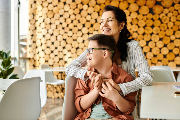 любящая красивая мать прекрасно проводит время со своим инклюзивным веселым сыном с синдромом Дауна в кафе - Фото, изображение