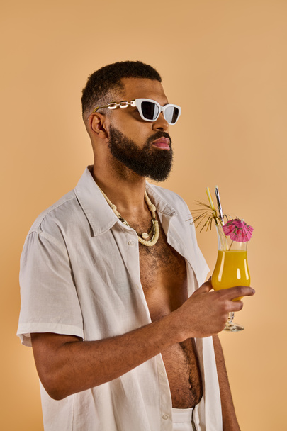 Стильный мужчина в солнечных очках наслаждается напитком в руке, источая атмосферу расслабления и изысканности. - Фото, изображение