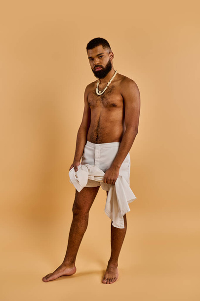 A bearded man stands confidently, draped in a white towel. His gaze is determined, exuding a sense of mystery and adventure. - Photo, Image