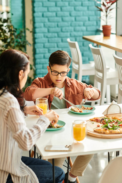 pozitivní matka jíst pizzu a pití šťávy s její inkluzivní roztomilý syn s Downovým syndromem - Fotografie, Obrázek