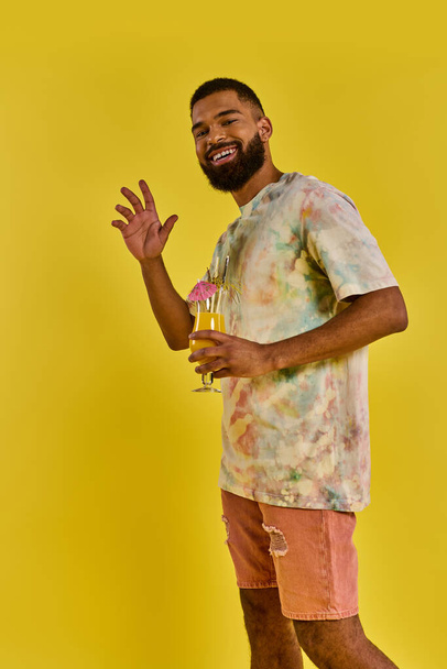 Ένας άντρας με ένα ποτήρι χυμό πορτοκάλι στο χέρι, απολαμβάνοντας το ζωηρό χρώμα και το αναζωογονητικό άρωμα του αναψυκτικού εσπεριδοειδών. - Φωτογραφία, εικόνα