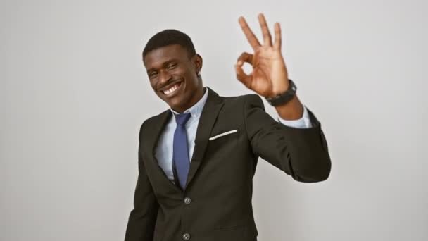Веселый африканский американец в костюме наносит положительный знак "ок" рукой, излучая уверенность и успех на изолированном белом фоне - Кадры, видео