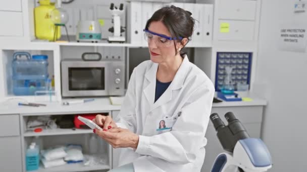 Mulher madura cientista usando smartphone em ambiente de laboratório - Filmagem, Vídeo