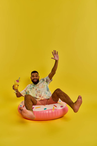 Um homem com uma expressão contemplativa senta-se no topo de um objeto inflável colorido, flutuando sem esforço na superfície das águas. - Foto, Imagem