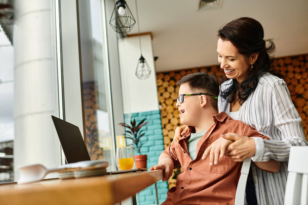 freudige Mutter verbringt Zeit mit ihrem inklusiven Sohn mit Down-Syndrom vor dem Laptop im Café - Foto, Bild