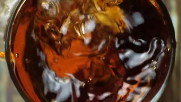Dos trozos de hielo cayendo en un vaso de coñac cámara lenta vista superior - Metraje, vídeo