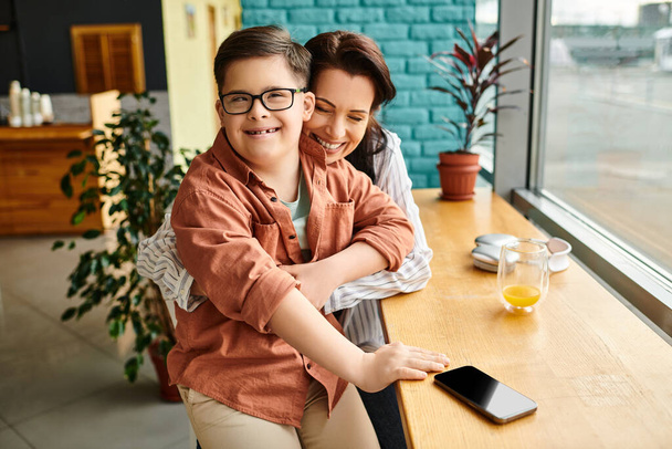 радостная мать проводит время со своим веселым сыном с синдромом Дауна со смартфоном - Фото, изображение