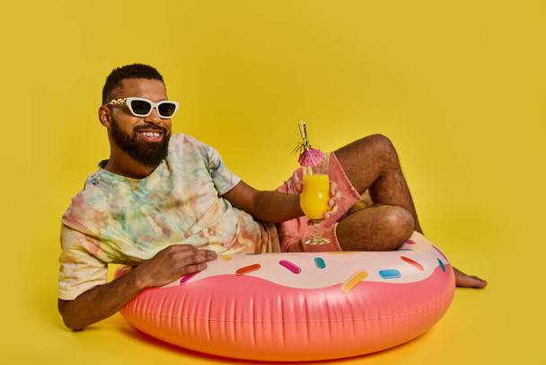 リラックスした姿勢の男が活気に満ちたピンクのドーナツフロートに座っていて,水に落ち着いた気分とレジャーを感じます.. - 写真・画像