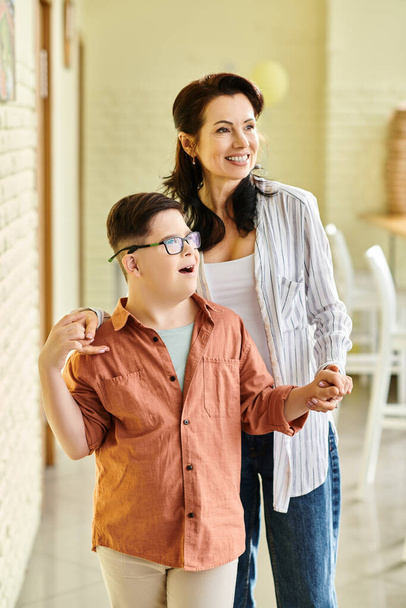 радостный очаровательный ребенок включительно мальчик с синдромом Дауна позирует со своей красивой веселой матерью - Фото, изображение