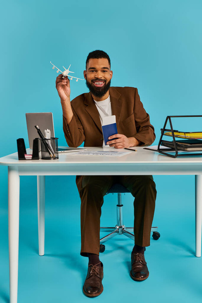 Un hombre se sienta en un escritorio, enfocado en la pantalla de su portátil. Él está escribiendo y navegando, rodeado por un espacio de trabajo lleno de papeles y suministros de oficina. - Foto, imagen