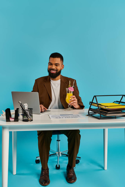 Um homem senta-se em uma mesa, absorvido em sua tela de laptop, ao lado de uma bebida, profundamente em pensamento e contemplação. - Foto, Imagem