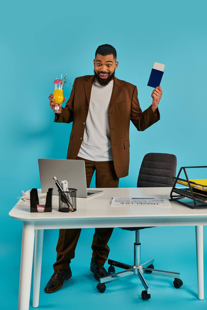 Un homme avec une expression sérieuse assis à un bureau, tenant une carte dans une main et tapant sur un ordinateur portable avec l'autre main. - Photo, image