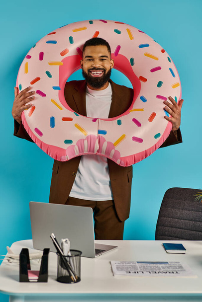 Ein Mann hält sich spielerisch einen riesigen Donut vor das Gesicht und blickt mit einem verschmitzten Lächeln durch das Loch. - Foto, Bild