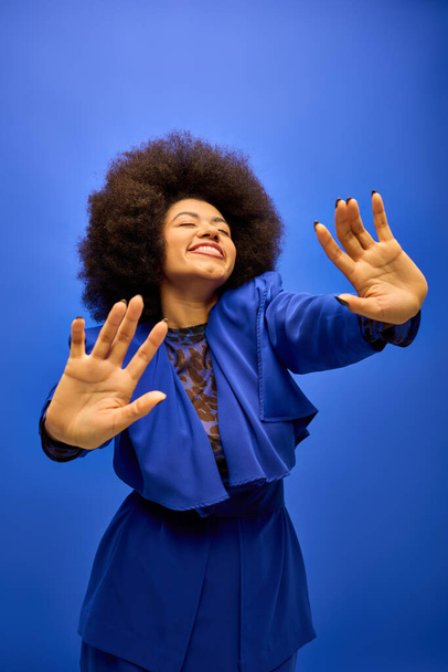 Una mujer afroamericana con estilo y cabello rizado hace un gesto de mano llamativo. - Foto, imagen